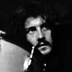 Black and white close-up of John Bonham looking up, with a drum in the foreground.