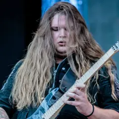 Tommy Johansson, con lunghi capelli biondi, suona la chitarra elettrica sul palco.