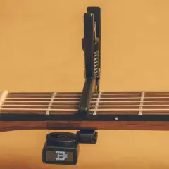 Chitarra acustica con capotasto 52 posizionato sulle corde. Il diapason digitale è agganciato sotto il manico.
