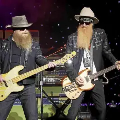 Due musicisti con lunghe barbe e cappelli suonano sul palco. Uno suona un basso giallo, l'altro una chitarra. È più facile suonare il basso o la chitarra?