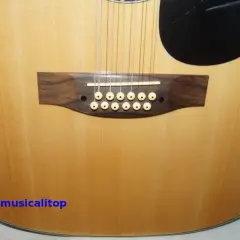 Chitarra acustica a 12 corde con ponte in legno scuro e materiale corde chitarra acustica in primo piano.