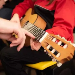 Mano guida un dito sulla tastiera, mostrando la corretta postura chitarra classica.