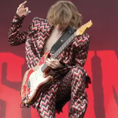 Thomas Raggi, chitarrista dei Måneskin, con la sua iconica chitarra rossa e un completo a zig-zag, infiamma il palco con la sua energia.
