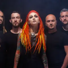 La band "Infected Rain" posa con look aggressivo. La cantante ha capelli rosso-giallo e tatuaggi colorati.