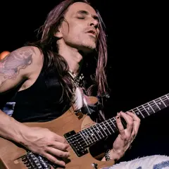 Nuno Bettencourt oggi, con occhi chiusi e capelli lunghi, suona la sua chitarra Washburn con passione.