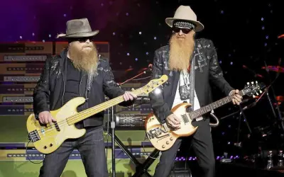 Due musicisti con lunghe barbe e cappelli suonano sul palco. Uno suona un basso giallo, l'altro una chitarra. È più facile suonare il basso o la chitarra?