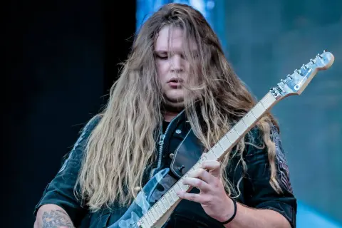 Tommy Johansson, con lunghi capelli biondi, suona la chitarra elettrica sul palco.