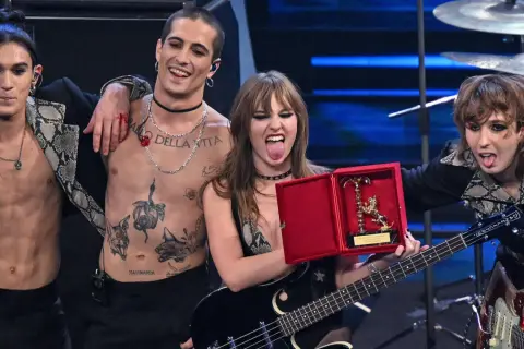 I Måneskin sciolti festeggiano con un premio, Damiano con il torace nudo e tatuato, Victoria con la lingua fuori, Thomas e Ethan con i capelli sciolti.