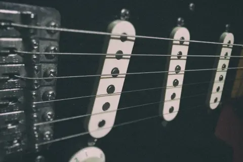 Dettaglio dei pickup di una Stratocaster, con le corde che passano sopra. L'altezza dei pickup è fondamentale per il suono.