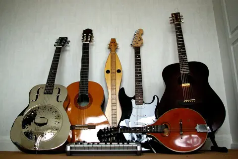 Una collezione di chitarre, tra cui una chitarra in metallo lucido, una acustica, una elettrica e un mandolino.