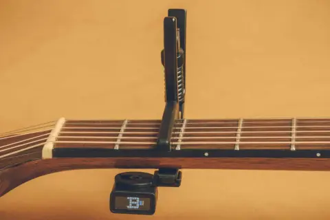 Chitarra acustica con capotasto 52 posizionato sulle corde. Il diapason digitale è agganciato sotto il manico.