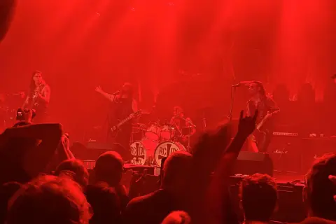 Concerto infuocato, la band sul palco, un chitarrista con i capelli lunghi, il batterista, il pubblico esulta. "Kata ton daimona eaytoy" risuona nell'aria.