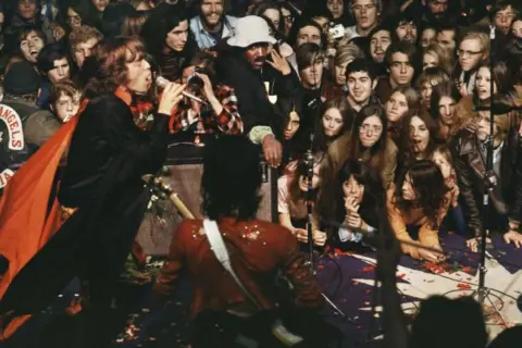 Concerto caotico con Mick Jagger che canta, la folla eccitata e i membri degli Hells Angels che sorvegliano. Un momento che fa "let it bleed".
