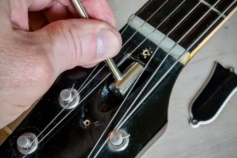 Regolazione del truss rod a doppia azione di una chitarra. La mano usa una chiave per agire sul meccanismo.