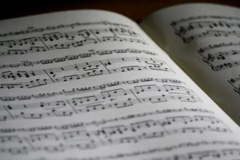Spartito musicale aperto con note, diesis e bemolle sul pentagramma. La musica attende di essere suonata.