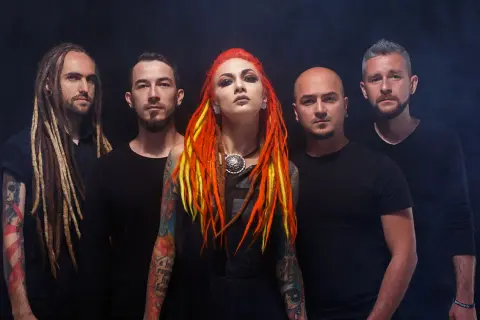 La band "Infected Rain" posa con look aggressivo. La cantante ha capelli rosso-giallo e tatuaggi colorati.