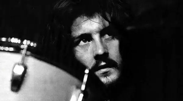Black and white close-up of John Bonham looking up, with a drum in the foreground.