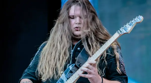 Tommy Johansson, con lunghi capelli biondi, suona la chitarra elettrica sul palco.