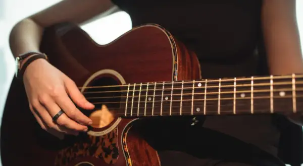 Mano che suona una chitarra acustica Takamine, con dettagli in tartaruga. Le opinioni su queste chitarre sono ottime.