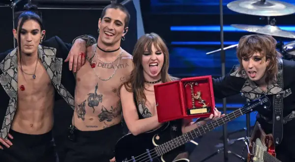 I Måneskin sciolti festeggiano con un premio, Damiano con il torace nudo e tatuato, Victoria con la lingua fuori, Thomas e Ethan con i capelli sciolti.