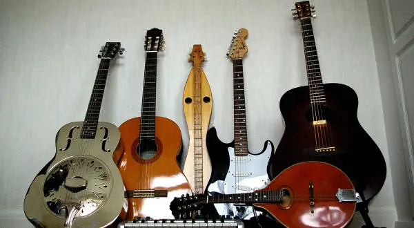 Una collezione di chitarre, tra cui una chitarra in metallo lucido, una acustica, una elettrica e un mandolino.