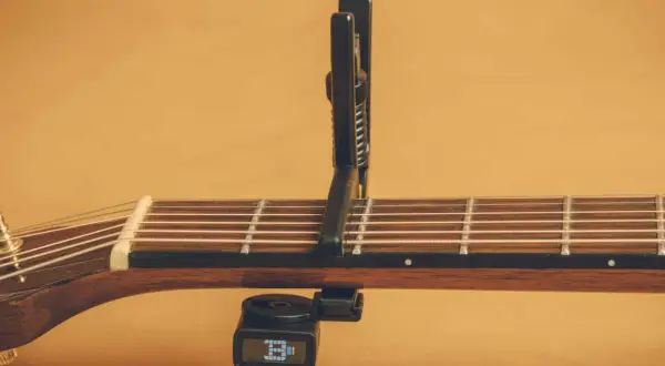 Chitarra acustica con capotasto 52 posizionato sulle corde. Il diapason digitale è agganciato sotto il manico.
