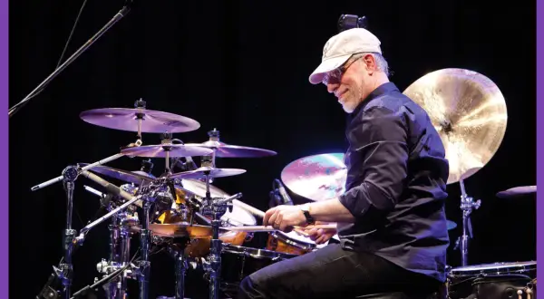 Dom Famularo, batterista con cappellino e occhiali, suona la batteria con passione.