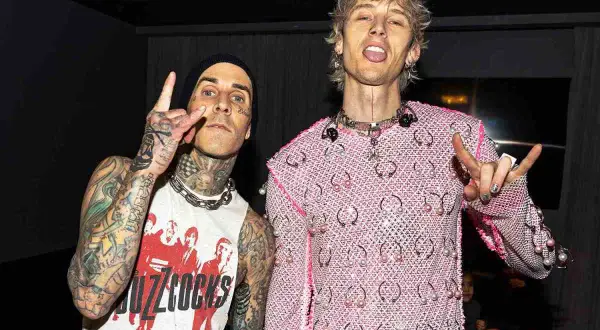Travis Barker e Machine Gun Kelly, co-compositori, posano con le mani alzate in segno di pace e corna.