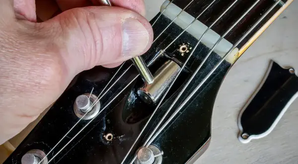 Regolazione del truss rod a doppia azione di una chitarra. La mano usa una chiave per agire sul meccanismo.