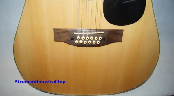 Chitarra acustica a 12 corde con ponte in legno scuro e materiale corde chitarra acustica in primo piano.