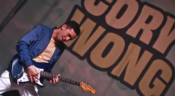 Cory Wong, chitarrista energico, suona la sua Fender con passione. Sullo sfondo, il suo nome in grandi lettere.