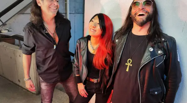 Tre musicisti con look rock, ispirati alle canzoni dei Guns N' Roses Chinese Democracy, sorridono e ridono.