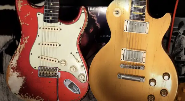 Iconiche chitarre: una Fender rossa consumata e una Gibson dorata, pronte per un duello musicale.