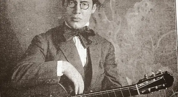 Ritratto di Andrés Segovia, chitarrista, con occhiali rotondi e papillon, mentre suona la sua chitarra.