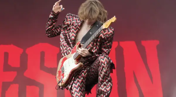 Thomas Raggi, chitarrista dei Måneskin, con la sua iconica chitarra rossa e un completo a zig-zag, infiamma il palco con la sua energia.