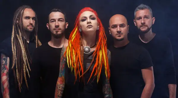 La band "Infected Rain" posa con look aggressivo. La cantante ha capelli rosso-giallo e tatuaggi colorati.