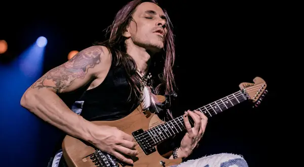 Nuno Bettencourt oggi, con occhi chiusi e capelli lunghi, suona la sua chitarra Washburn con passione.