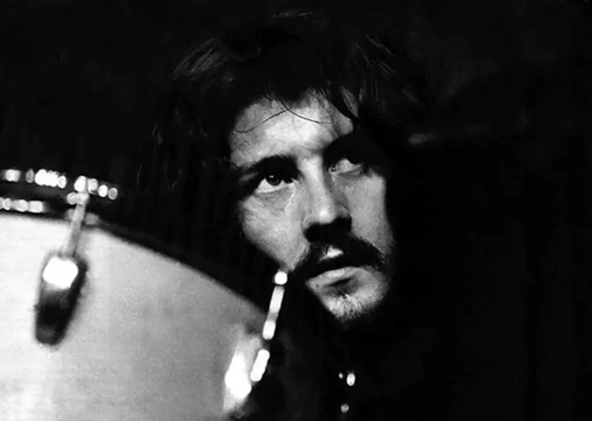 Black and white close-up of John Bonham looking up, with a drum in the foreground.