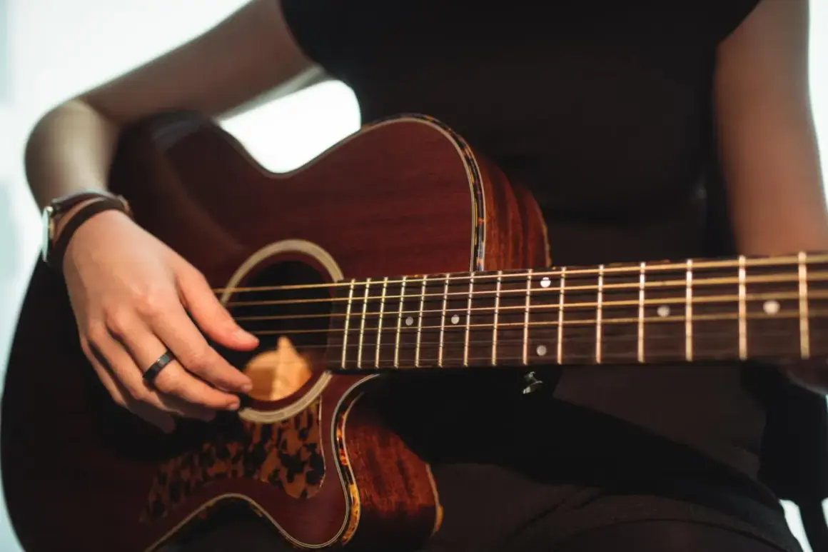 Mano che suona una chitarra acustica Takamine, con dettagli in tartaruga. Le opinioni su queste chitarre sono ottime.