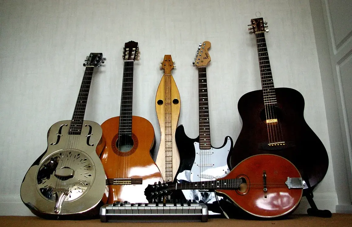 Una collezione di chitarre, tra cui una chitarra in metallo lucido, una acustica, una elettrica e un mandolino.