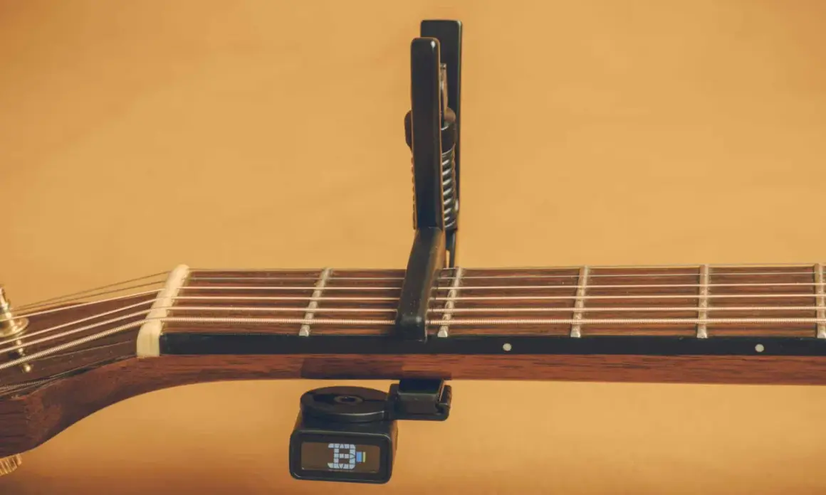 Chitarra acustica con capotasto 52 posizionato sulle corde. Il diapason digitale è agganciato sotto il manico.