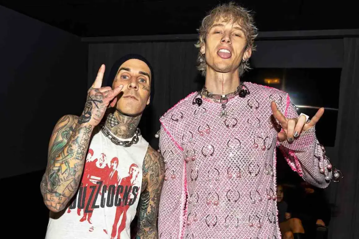 Travis Barker e Machine Gun Kelly, co-compositori, posano con le mani alzate in segno di pace e corna.