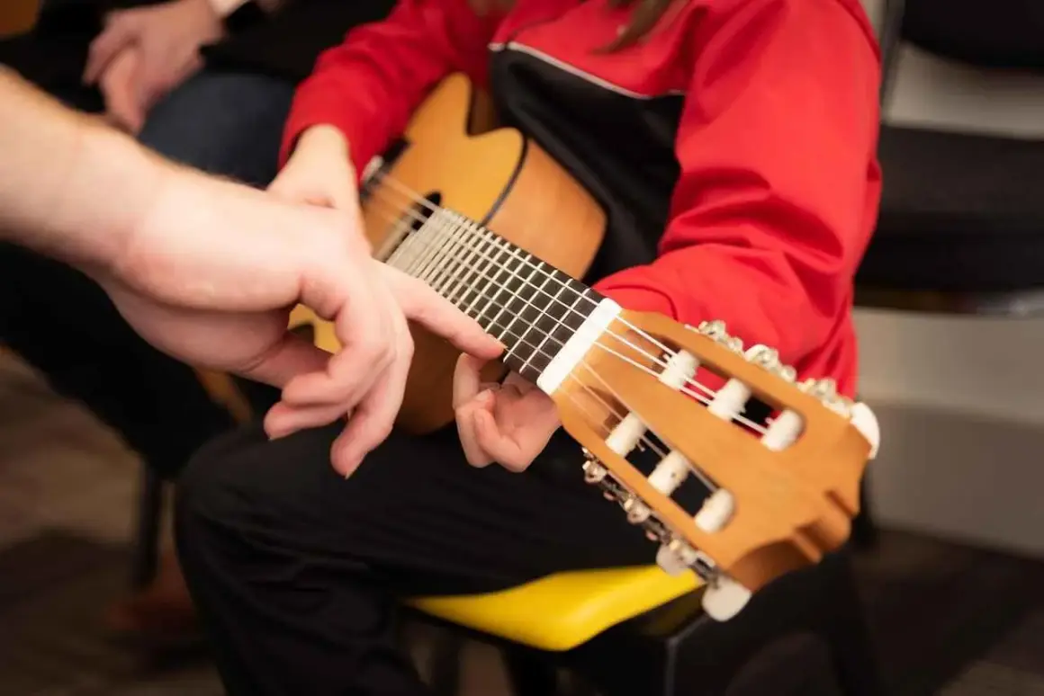 Mano guida un dito sulla tastiera, mostrando la corretta postura chitarra classica.