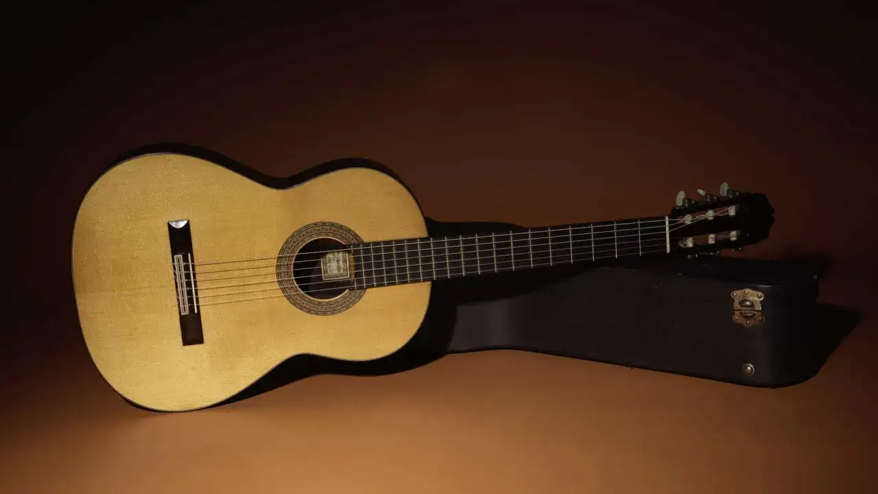 Chitarra classica in legno chiaro, pronta per essere suonata dal chitarrista Segovia. Custodia scura a lato.