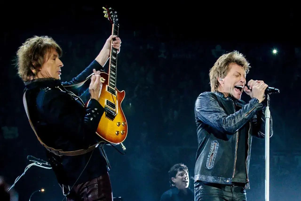 Il chitarrista dei Bon Jovi suona con passione mentre Jon Bon Jovi canta sul palco.