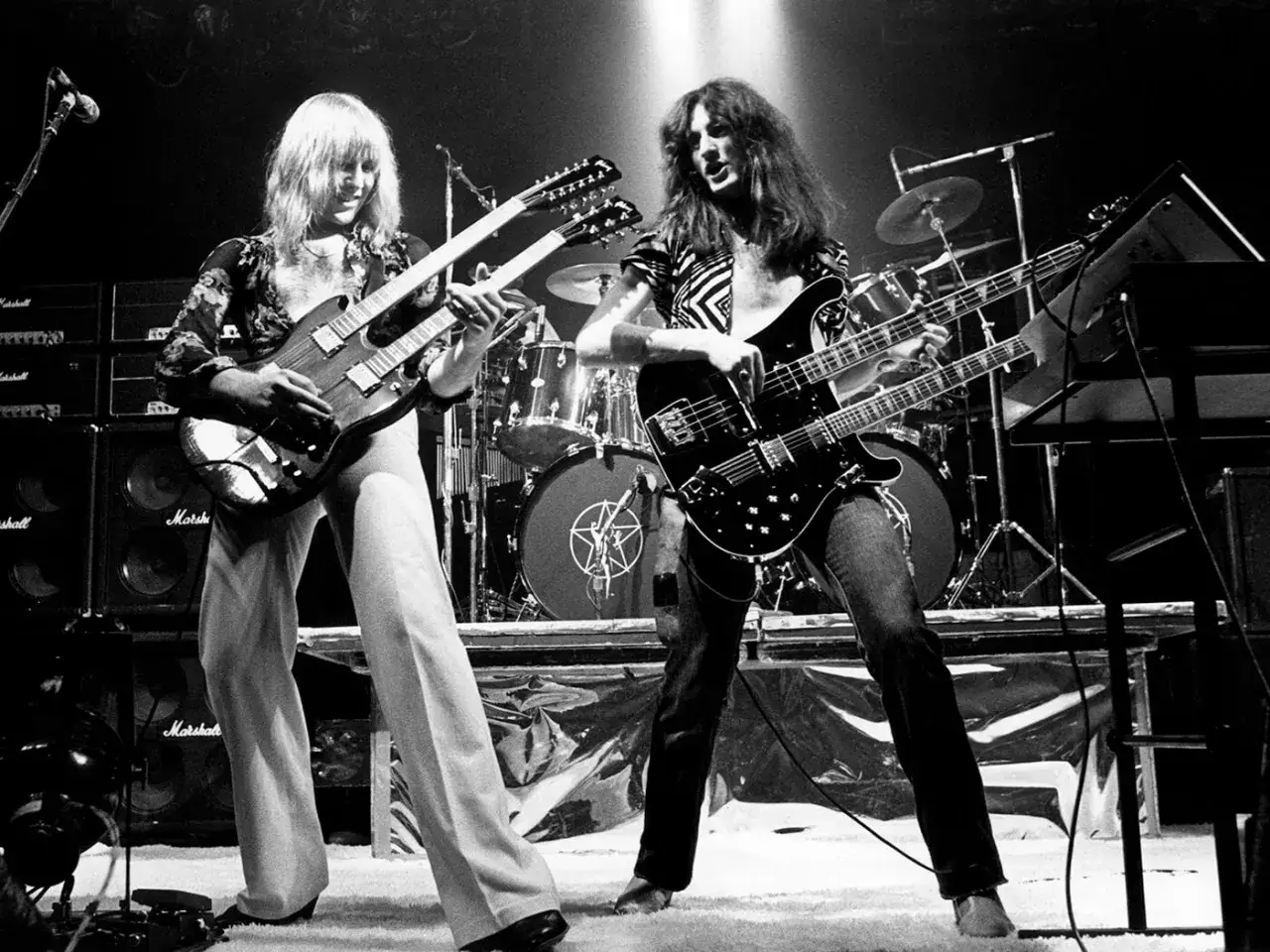 Due chitarristi sul palco, uno con una chitarra doppio manico, l'altro con un basso doppio manico, in un concerto rock.