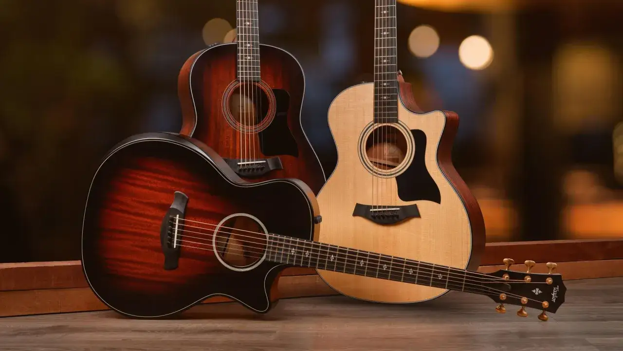 Tre chitarre acustiche Taylor, una chiara e due scure, pronte per essere suonate. Le opinioni su queste chitarre sono sempre positive.