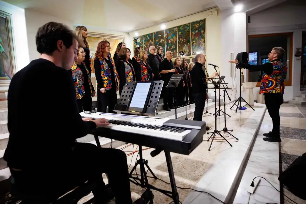 Un coro di adulti si esibisce con passione, un pianista accompagna la melodia. Un esempio di come studiare musica da adulti possa portare gioia e armonia.