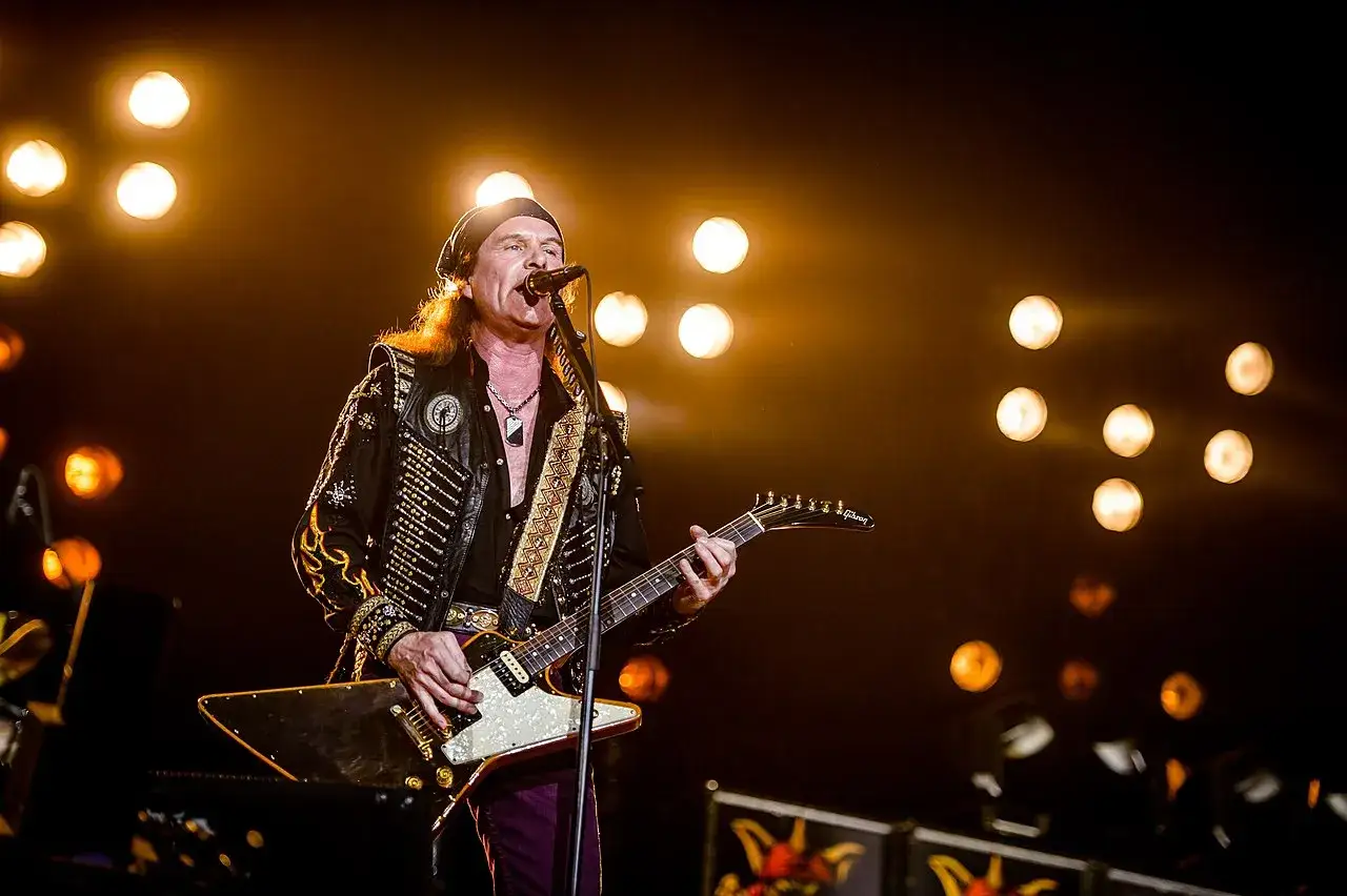 Chitarrista dei Running Wild Band sul palco, illuminato da luci calde, con la sua chitarra iconica.