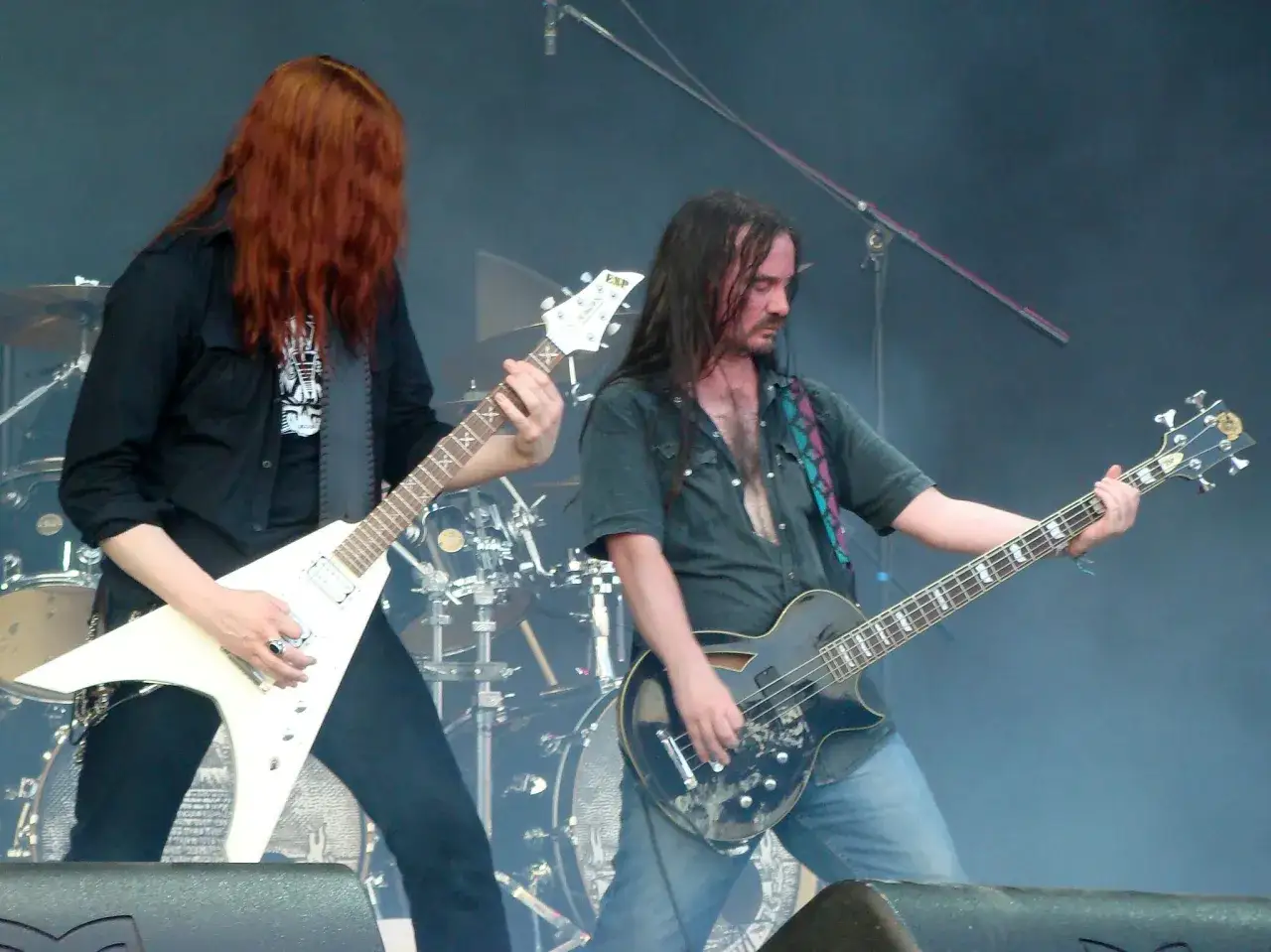Due chitarristi su un palco, uno con lunghi capelli rossi e una chitarra bianca a forma di V, l'altro con capelli scuri e una chitarra nera. Un'atmosfera di dark tranquillity.
